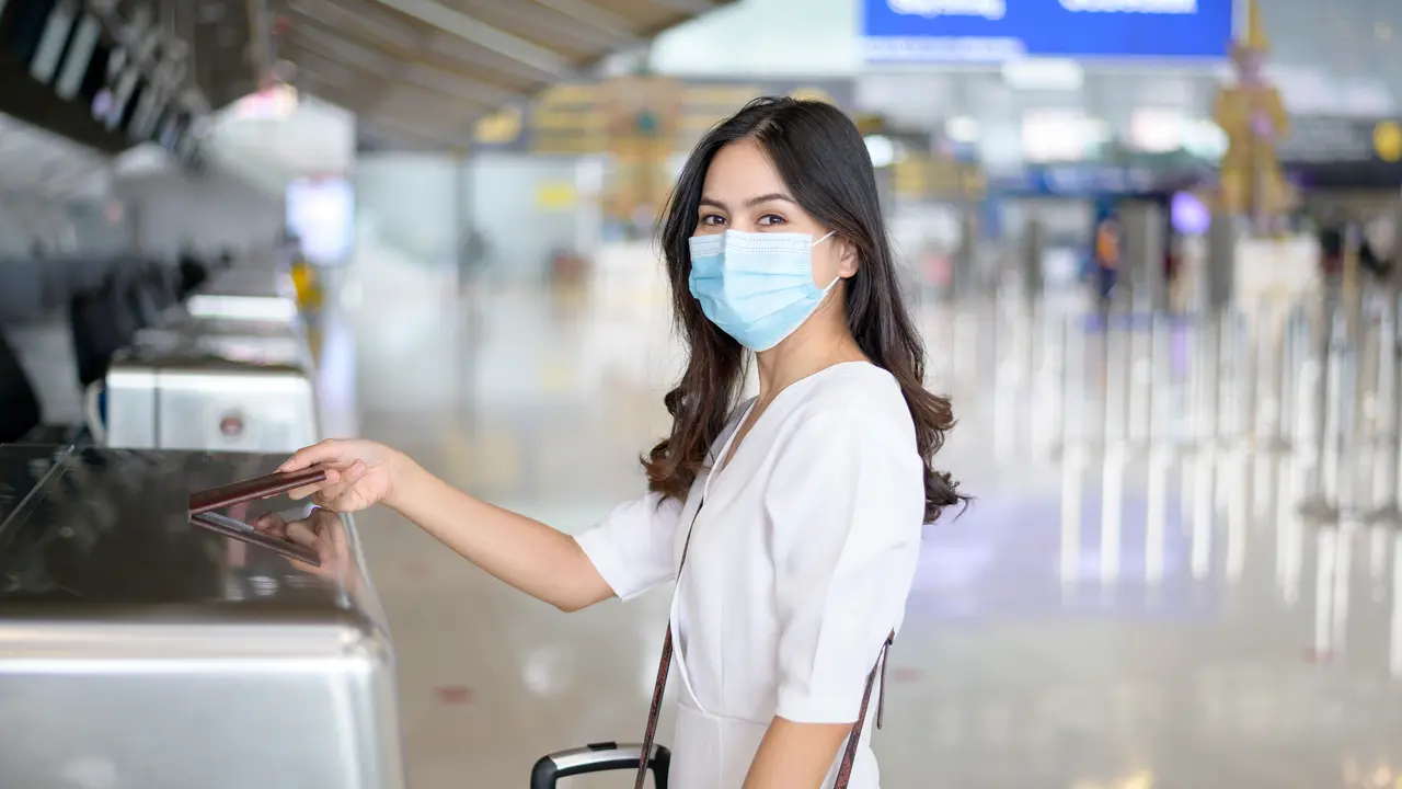perempuan di bandara traveling pakai masker