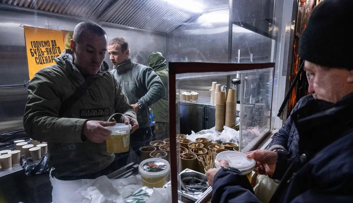 Di Kyiv, pemadaman listrik menyebabkan terhentinya sistem pemanas sentral dan air bersih bagi ribuan gedung apartemen. Tampak dalam foto, para veteran the 3rd Separate Assault Brigade Angkatan Bersenjata Ukraina menyajikan makanan panas gratis bagi orang-orang di lingkungan perumahan yang rumahnya tanpa listrik setelah serangan udara Rusia berulang kali terhadap sektor energi negara itu di Kyiv, Selasa 27 Januari 2026. (AP Photo/Danylo Antoniuk)