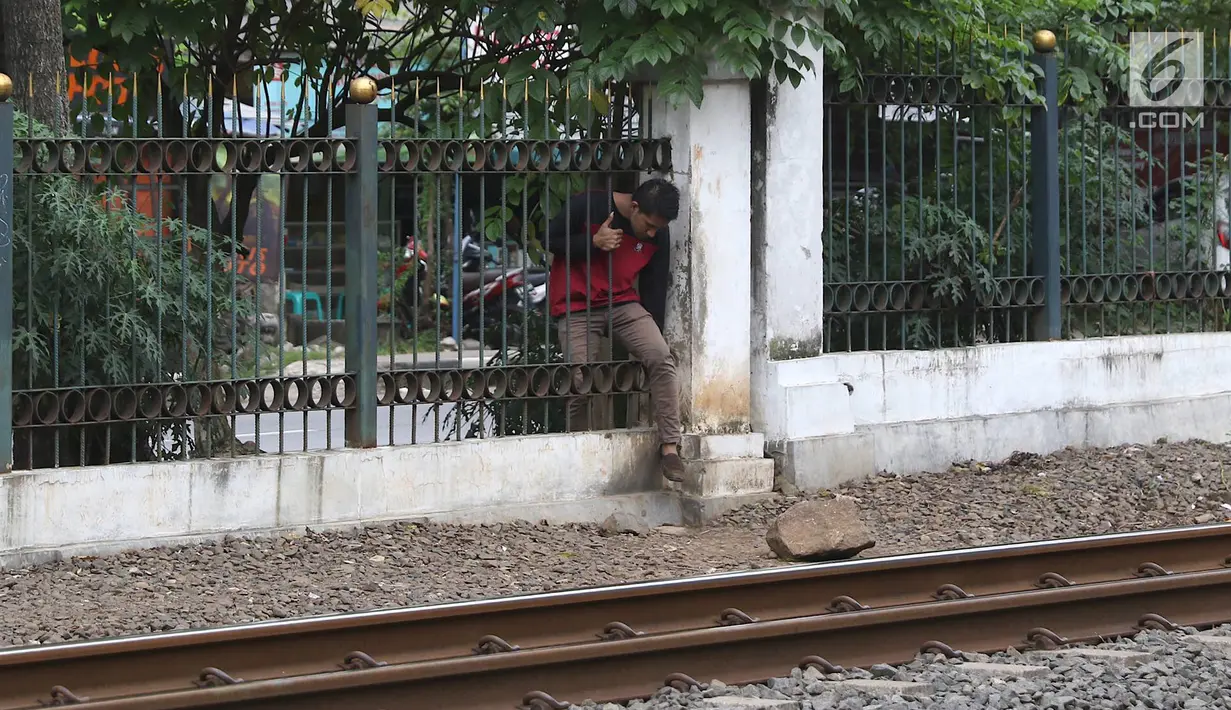 Warga menerobos pagar untuk menyeberangi rel kereta api di kawasan Lenteng Agung, Jakarta, Selasa (19/3). Tidak adanya JPO menyebabkan warga harus menerobos pagar besi, meskipun perilaku tersebut berbahaya bagi keselamatan.(Liputan6.com/Immanuel Antonius)