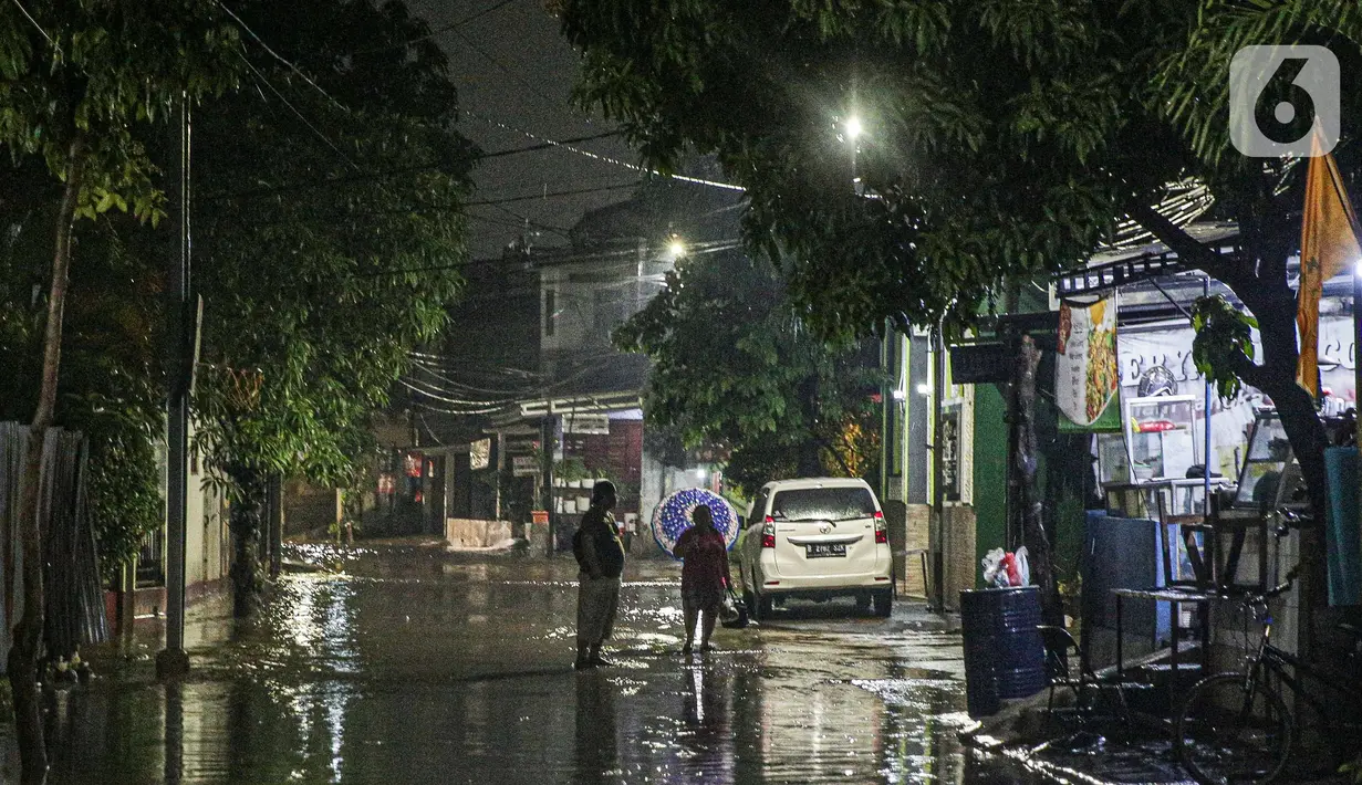 Warga melintas di genangan banjir di kawasan Mampang Prapatan, Jakarta, Sabtu (13/11/2021). Intensitas hujan yang tinggi sejak sore di Jakarta membuat kawasan permukiman di Mampang Prapatan tergenang banjir dengan tinggi sebetis orang dewasa. (Liputan6.com/Faizal Fanani)