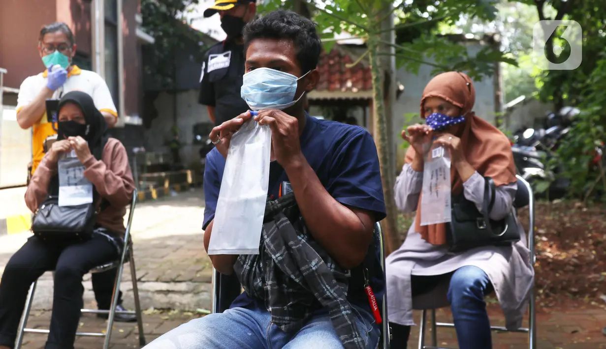 Warga meniupkan kantong saat menjalani tes deteksi COVID-19 dengan metode GeNose C19 usai terjaring razia penggunaan masker di Kelurahan Sudimara Barat, Kota Tangerang, Kamis (27/5/2021). Tes tersebut untuk menekan penyebaran corona di wilayah tersebut. (Liputan6.com/Angga Yuniar)