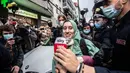 Petugas bantuan Italia Silvia Romano, dikawal Carabinieri, melepaskan masker saat konferensi pers setibanya di rumahnya di Milan, 11 Mei 2020. Terkait keputusan menjadi mualaf, Silvia dengan tegas mengatakan telah bersyahadat selama penculikan dan itu pilihannya tanpa paksaan. (AP/Luca Bruno)