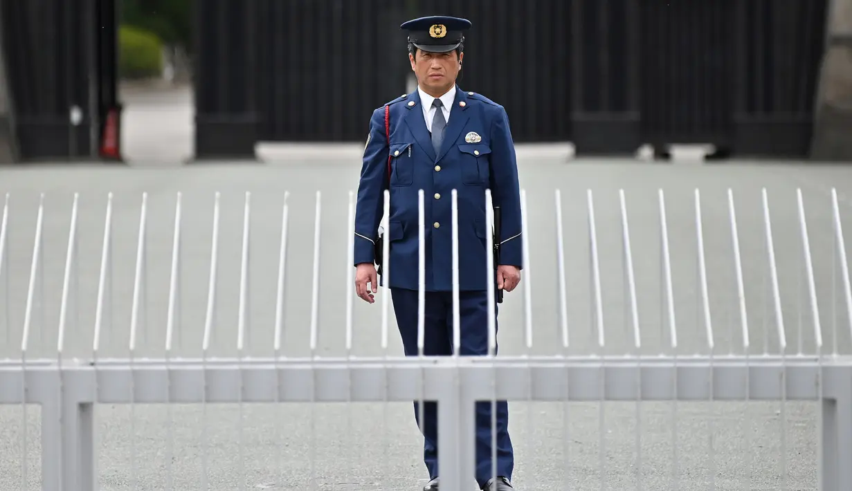 Polisi berdiri di depan pintu masuk halaman Istana Kekaisaran Jepang (29/4/2019). Kaisar Jepang Akihito akan turun dari Tahta Krisan pada 30 April 2019 mengakhiri 30 tahun masa pemerintahannya. (Charly Triballeau / AFP)