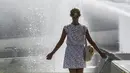 Seorang wanita menikmati air mancur di sebuah kolam di Trocadero Fountains, Paris (22/7/2019). Warga Paris bersiap menghadapi suhu terpanas pada minggu ini ketika gelombang panas akan melanda ke Eropa utara. (AFP Photo/Alain Jocard)