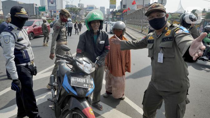 Petugas memberhentikan pengendara sepeda motor yang tidak mengenakan masker di kawasan Jalan Ir. H. Juanda, Depok, Jawa Barat, Kamis (23/7/2020). Razia tersebut dilakukan oleh tim gabungan dari Polresta Depok dan Satpol PP. (merdeka.com/Arie Basuki)