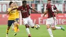 Pemain AC Milan, Franck Kessie (tengah) melepaskan tembakan saat di adang pemain Hellas Verona, Seung-Woo Lee (kiri) pada lanjutan Serie A di San Siro stadium, Milan, (5/5/2018). AC Milan menang telak 4-1. (AFP/Miguel Medina)