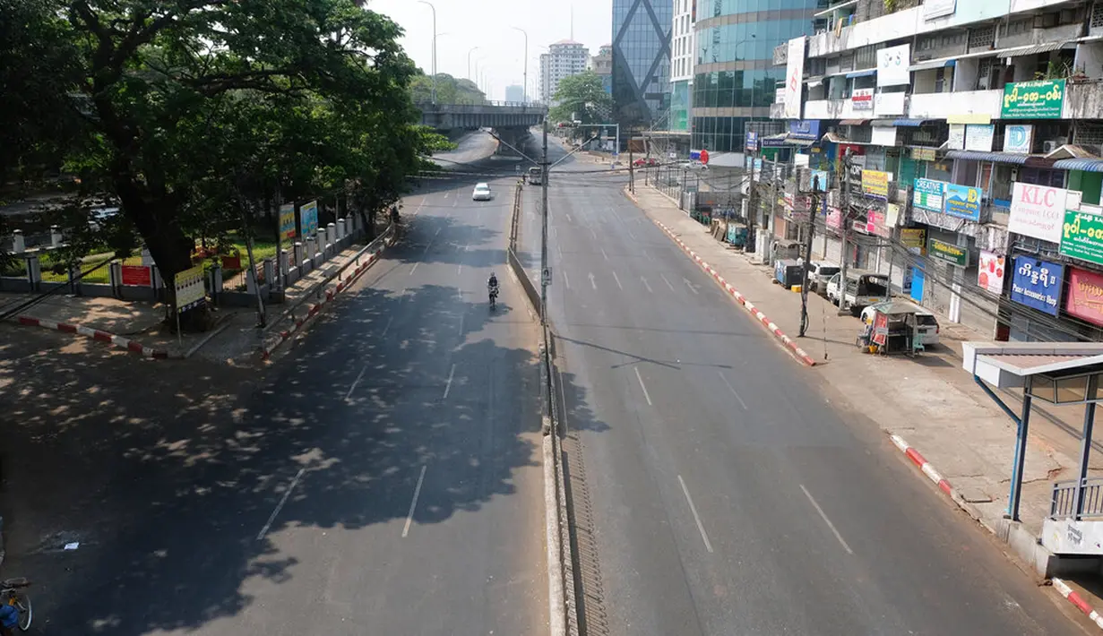 Seorang pengendara sepeda motor dan mobil melintasi jalanan yang kosong di pusat Kota Yangon, Myanmar, Rabu (24/3/2021. Demonstran antikudeta mencoba taktik baru yang mereka sebut pemogokan 'diam', menyerukan orang-orang untuk tinggal di rumah dan menutup bisnis. (AP Photo)
