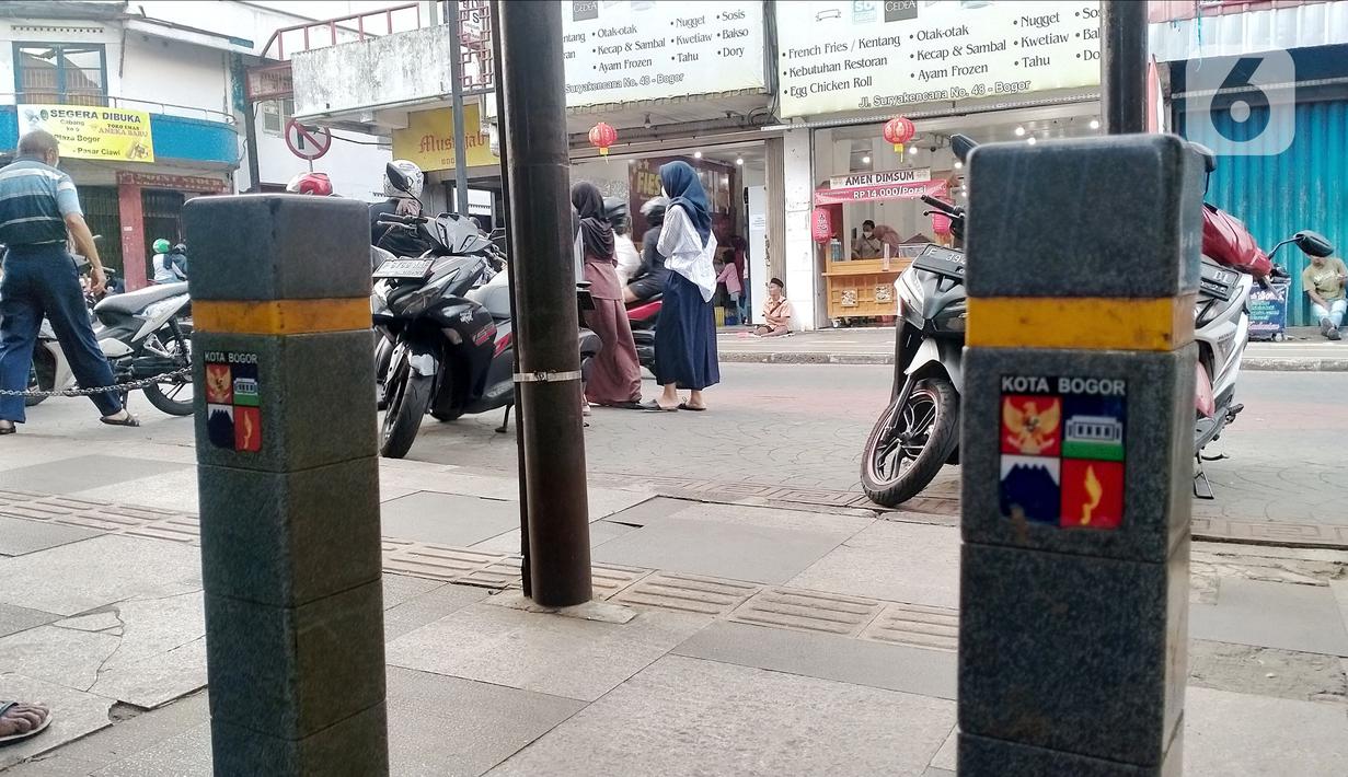 Tiang berdiri di jalur disabilitas pedestrian sepanjang Jalan Surya Kencana, Kota Bogor, Jawa Barat, Sabtu (3/12/2022). Jalur pedestrian yang seharusnya menjadi akses pejalan kaki dan ramah bagi kaum disabilitas itu tidak berfungsi dengan semestinya. (Liputan6.com/Magang/Aida Nuralifa)