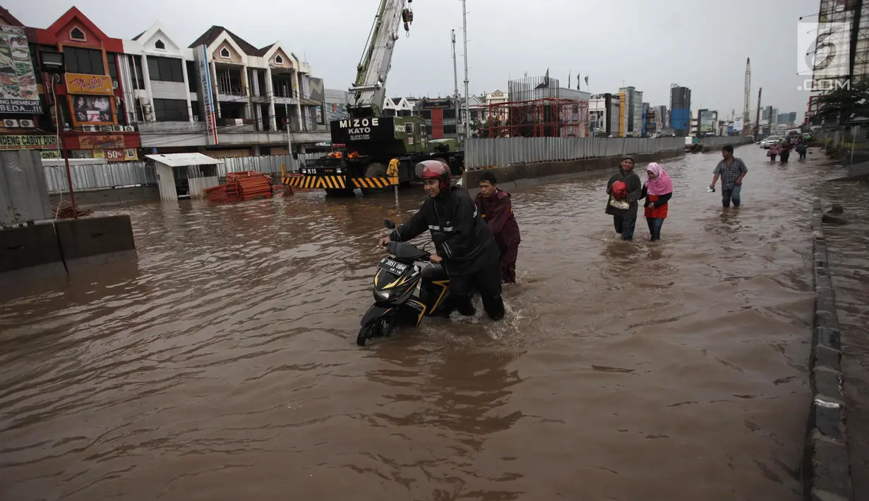 Pengendara mendorong sepeda motornya saat melintasi banjir di Jalan Boulevard Barat Raya, Kelapa Gading, Jakarta, Kamis (15/2). Hujan lebat sejak pagi hingga sore hari mengakibatkan sejumlah wilayah Ibu Kota terendam banjir. (Liputan6.com/Arya Manggala)