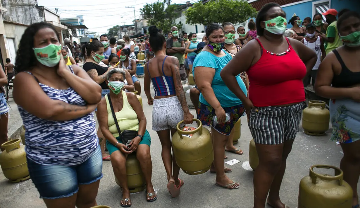 Warga memakai masker saat antre membeli gas murah dari Petrobrás Oil Tankers Union di favela Vila Vintem, Rio de Janeiro, Brasil, Jumat (12/3/2021). Kegiatan ini sebagai kampanye solidaritas untuk memperingati Hari Perjuangan Nasional Pertahanan Perusahaan Milik Negara. (AP Photo/Bruna Prado)