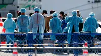 Petugas memeriksa penumpang yang turun dari kapal pesiar Diamond Princess yang dikarantina di Yokohama, Jepang, Jumat (21/2/2020). Dua orang Jepang dari kapal pesiar Diamond Princess dilaporkan meninggal dunia. (AP Photo/Eugene Hoshiko)