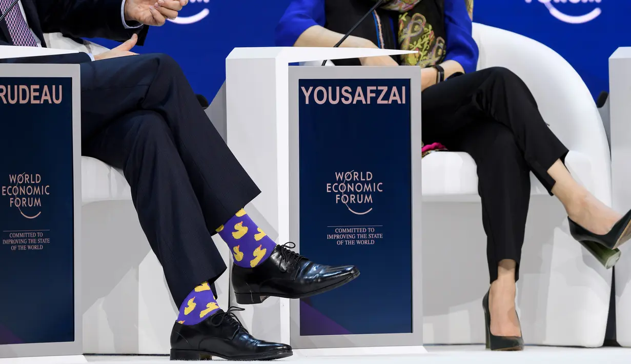 Kaus kaki PM Kanada Justin Trudeau terlihat saat sesi bersama peraih Nobel Malala Yousafzai pada acara tahunan World Economic Forum di Davos, Swiss, Kamis (25/1). Kaus kaki terlihat kala dia mengangkat salah satu kakinya. (Fabrice COFFRINI/AFP)