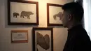 Seorang pengunjung melihat-lihat karya dalam pameran seni badak Sumatera di Perpustakaan Nasional Indonesia, Jakarta Pusat, Jumat (19/1). Pameran bertajuk 'Harta Karun Tersembunyi Indonesia' ini akan berlangsung tiga hari. (Liputan6.com/Arya Manggala)