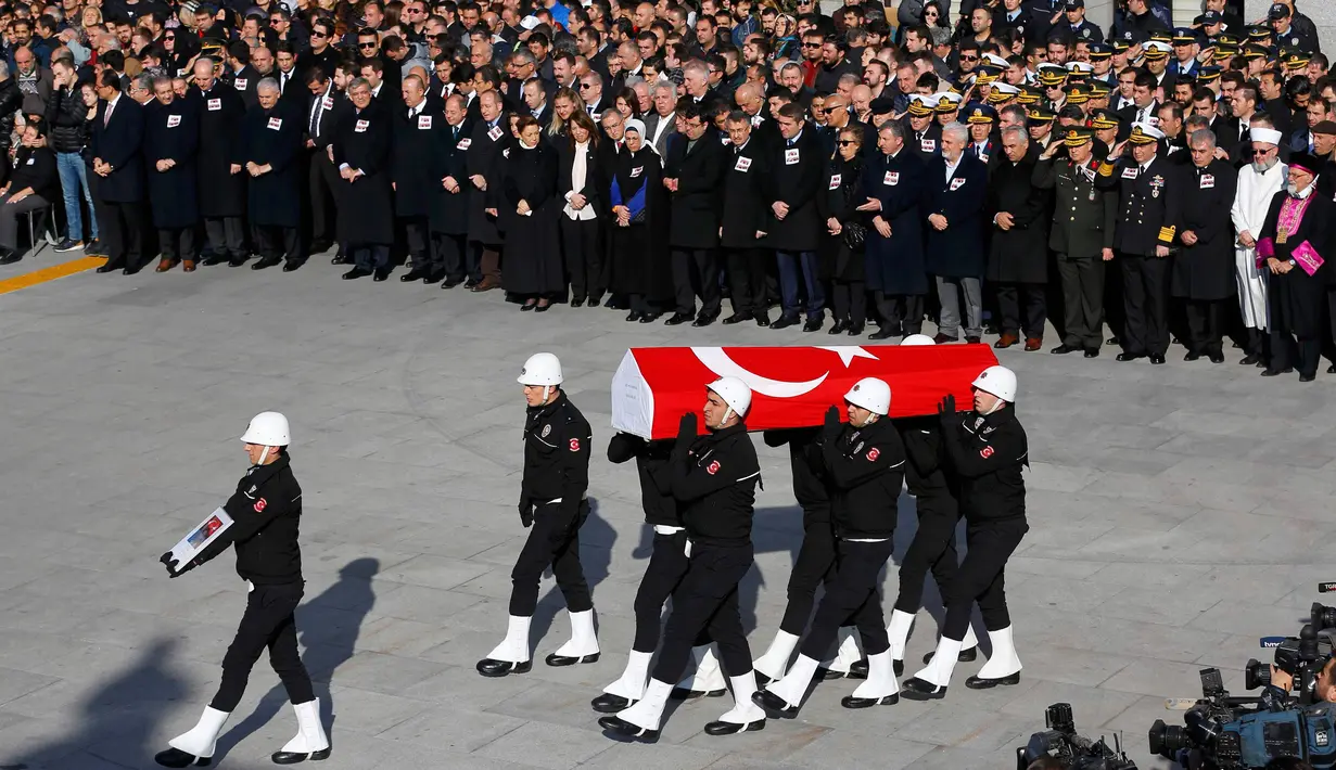 Petugas kepolisian membawa peti mati dengan bendara Turki saat upacara pemakaman anggota Polisi yang tewas dalam ledakan bom di Istanbul, Turki (11/12). (Reuters/Murad Sezer)
