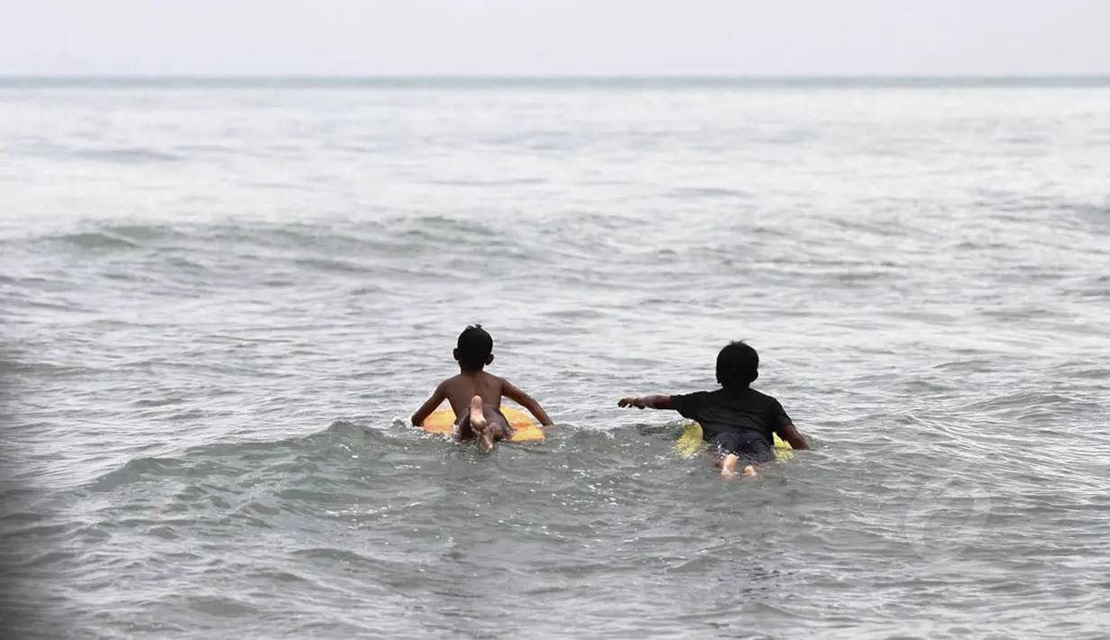 Di pantai pesisir Karang Bolong, Banten, beberapa anak nelayan mencoba keberanian dengan bermain selancar (Liputan6.com/Faizal Fanani) 