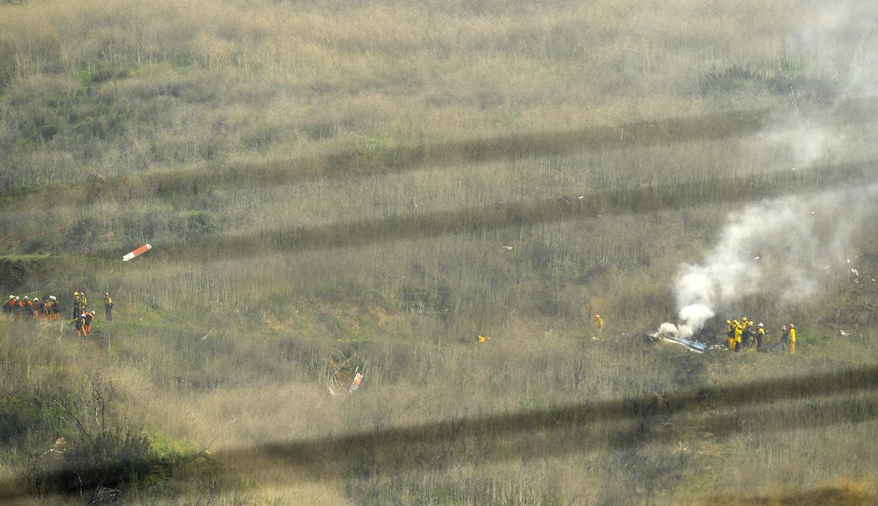 Sejumlah petugas berusaha mengevakuasi korban jatuhnya helikopter di Calabasas, California, Minggu (26/1/2020). Legenda NBA, Kobe Bryant, menjadi salah satu korban tewas pada kecelekaan helikopter berjenis Sikorsky S-76B itu. (AP/Mark J. Terrill)