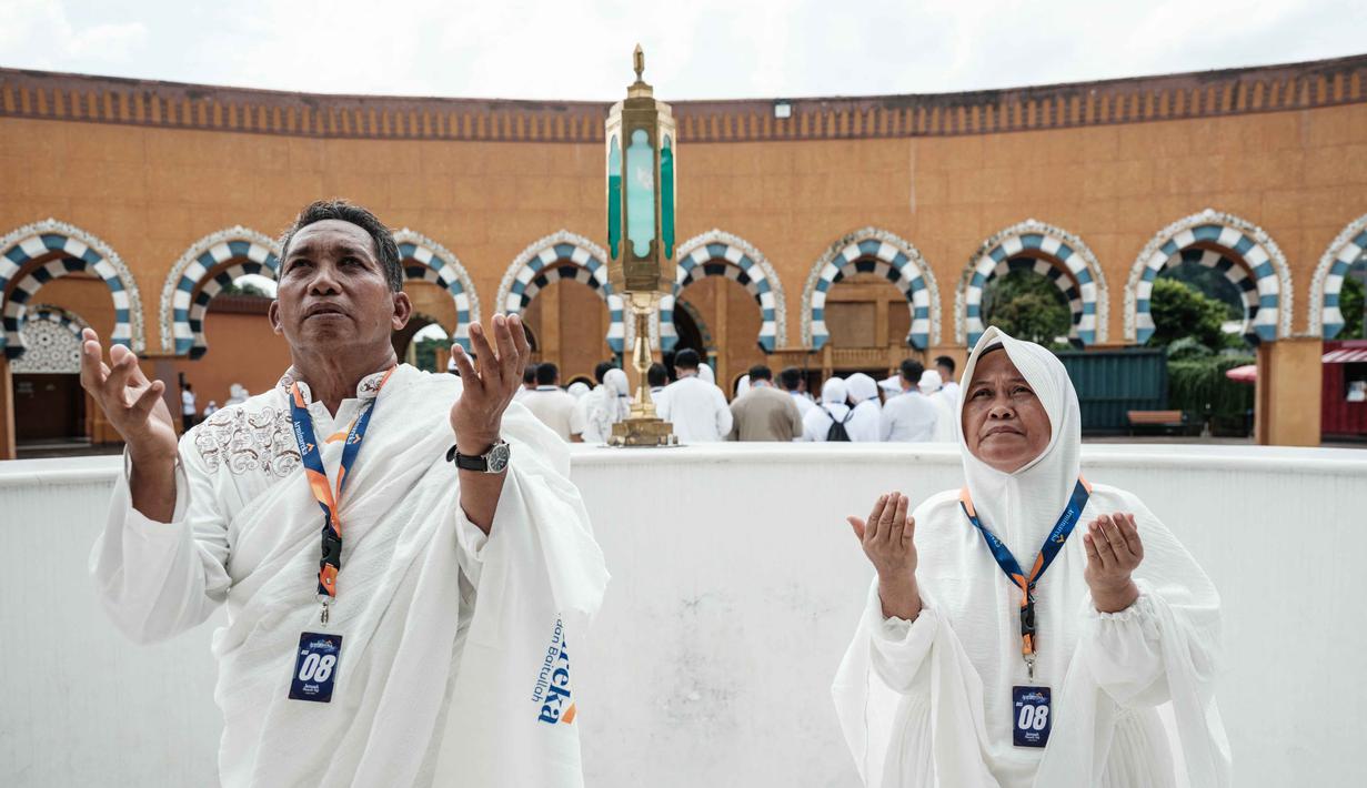 Diketahui, harga bahan bakar pesawat (avtur) mengalami lonjakan, dari Rp 13.656 menjadi Rp 23.551 per liter, sebagai imbas konflik yang terjadi di Timur Tengah. Tampak dalam foto, sepasang suami istri melakukan ritual di replika Ka'bah, saat mengikuti pelatihan di Pusat Pelatihan Manasik Al Mahmudah (AMTC), fasilitas pelatihan Haji yang menampilkan replika situs-situs ziarah utama, di Tangerang Selatan pada 5 April 2026. (YASUYOSHI CHIBA/AFP)