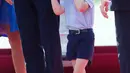 Pangeran George menggenggam tangan sang ayah, Pangeran William setibanya di Bandara Tegel, Berlin, Rabu (19/7). Ikut dalam tur keluarga kerajaan Inggris, Pangeran George kelihatan lelah dan mengantuk saat turun pesawat. (Steffi Loos/Pool Photo via AP)