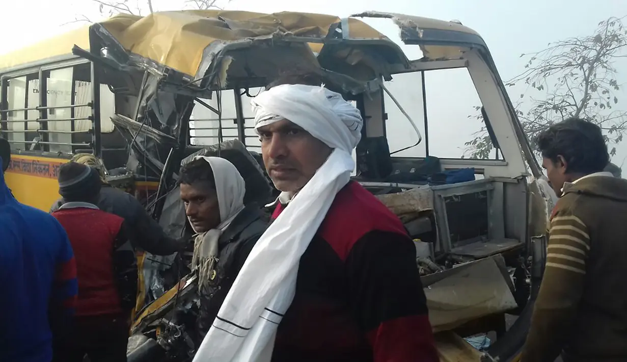 Warga berdiri di samping bus sekolah yang ringsek setelah mengalami tabrakan dengan truk di Etah, negara bagian Uttar Pradesh, India, Kamis (19/1). Bus sekolah itu diketahui mengangkut siswa Aliganj Public School saat tabrakan terjadi. (AFP PHOTO/STR)