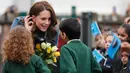 The Duchess of Cambridge, Kate Middleton menerima hadiah bunga dari anak-anak saat berkunjung ke Roe Green Junior School di London, Inggris, Selasa (23/1). (AP Photo/Frank Augstein)