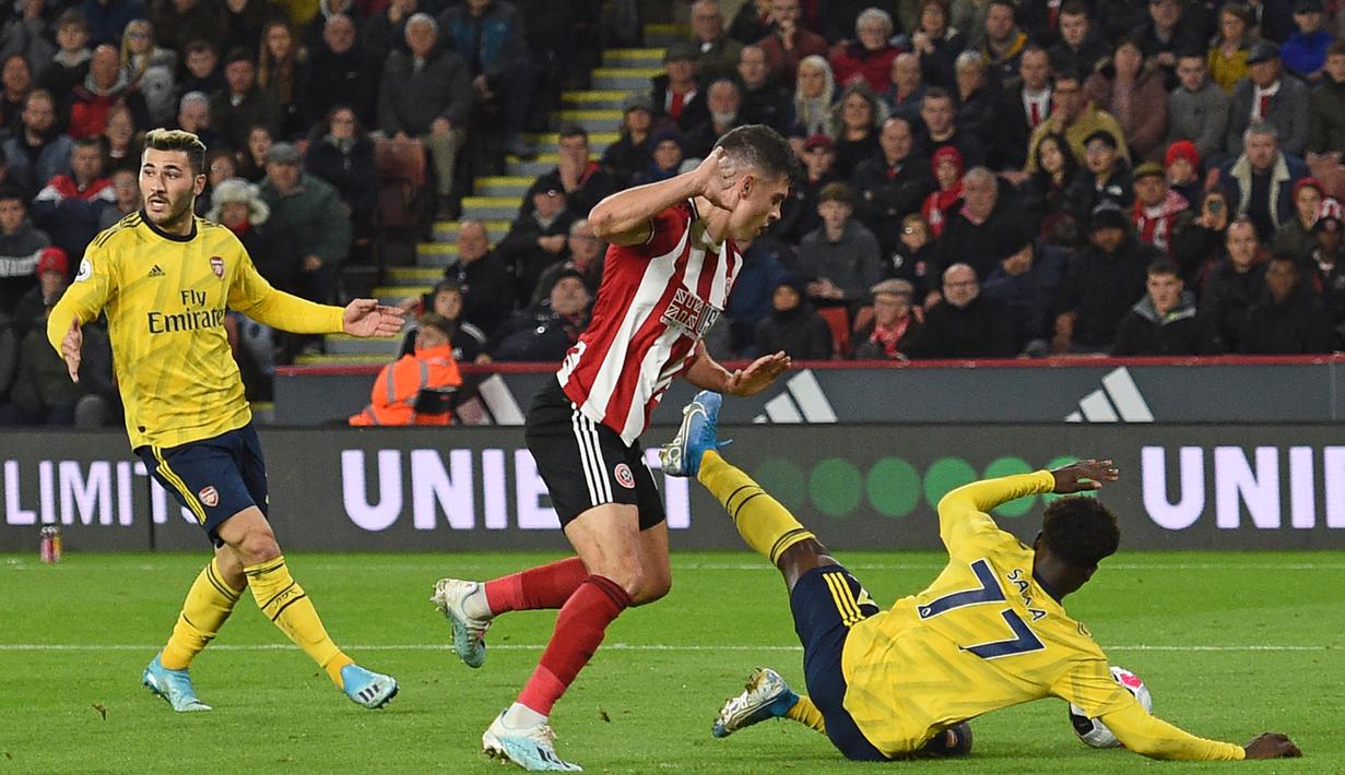 Bek Sheffield United, John Egan, berebut bola dengan striker Arsenal, Bukayo Saka, pada laga Premier League di Stadion Bramall Lane, Sheffield, Senin (21/10). Sheffield menang 1-0 atas Arsenal. (AFP/Oli Scarff)