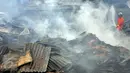 Petugas pemadam kebakaran mencoba memadamkan bara api yang masih tersisa di puing-puing rumah di Jalan Gotong Royong, RW 002 Pondok Bambu, Jakarta, Senin (8/8). Tiga orang terluka dalam kebakaran yang menghanguskan 90 rumah itu. (Liputan6.com/Johan Tallo)