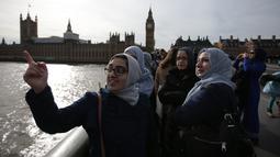 Para perempuan dari beragam etnis mengenakan warna biru berkumpul di Jembatan Westminster, London, Minggu (26/3). Mereka melakukan aksi solidaritas mengenang korban teror London dengan saling bergandengan tangan selama lima menit. (Daniel LEAL-OLIVAS/AFP)