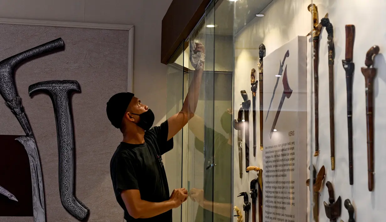 Seorang pekerja membersihkan etalase yang memajang keris jelang pameran persenjataan tradisional di Museum Aceh, Banda Aceh, Aceh, Jumat (15/10/2021). Pameran Senjata 2021 menampilkan 176 jenis senjata yang merupakan koleksi Museum Aceh. (CHAIDEER MAHYUDDIN/AFP)
