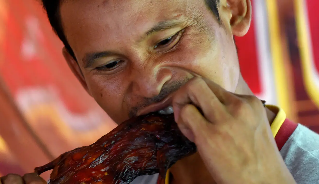 Seorang pria memakan tikus bakar di sebuah kios di provinsi Battambang, Kamboja (8/8/2019). Tikus bakar yang tusuk sate harganya masing-masing 0,25 USD atau sekitar 3500 rupiah. (AFP Photo/Tang Chhin Sotthy)