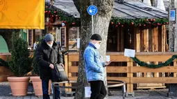 Sejumlah pria berdiri di bawah tanda yang mengingatkan warga untuk memakai masker di Munich (11/12/2020). Kasus penularan dan kematian harian COVID-19 di Jerman terus meningkat dan mencapai rekor tertinggi baru pada Jumat (11/12), menurut data dari Robert Koch Institute (RKI). (Xinhua/Philippe Ruiz)