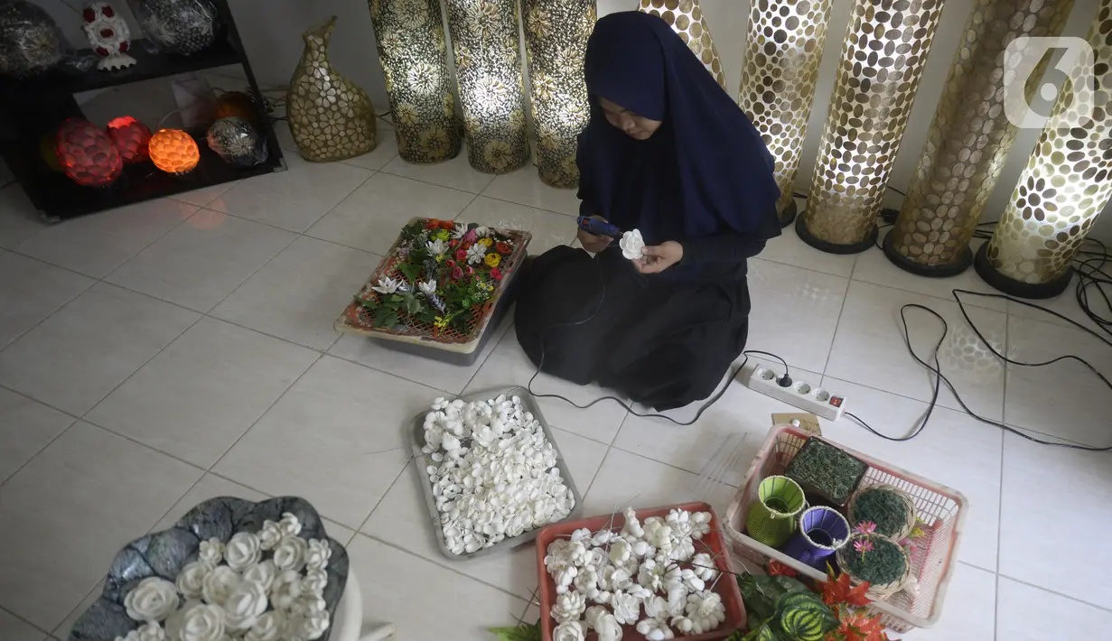 Perajin menyelesaikan pembuatan kerajinan tangan dari kulit kerang di Pamulang 2, Tangerang Selatan, Banten, Senin (20/7/2020). Aneka kerajinan tangan dengan motif bunga hingga ikan tersebut diolah dari limbah kulit kerang. (merdeka.com/Dwi Narwoko)
