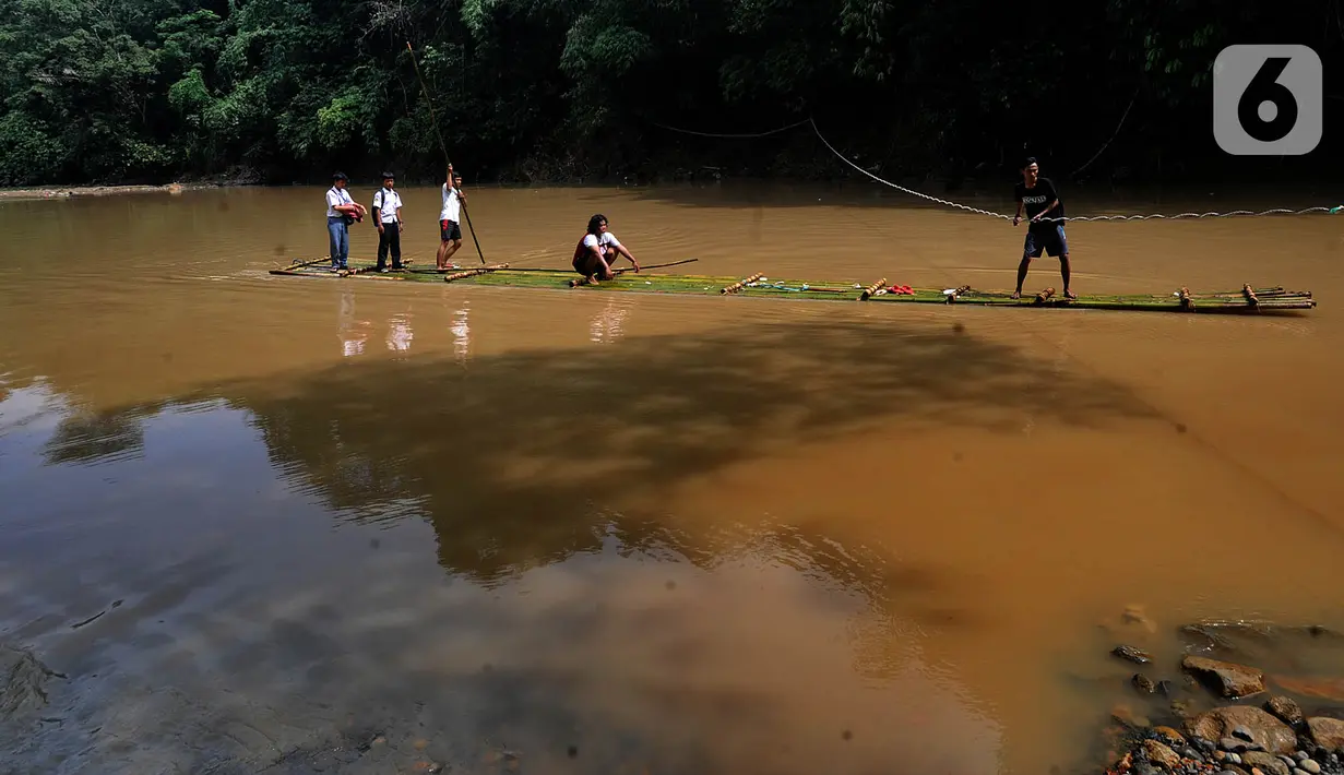 Sejumlah siswa menyeberangi Sungai Cikaniki dengan rakit di Rumpin, Bogor, Jawa Barat, Rabu (15/1/2020). Akibat banjir bandang merobohkan jembatan yang menghubungkan Desa Tonjong Rumpin dan Desa Kantalarang Leuwiliang, warga terpaksa memanfaatkan perahu rakit untuk melintas (merdeka.com/Arie Basuki)