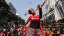 Seorang penari diikuti ribuan peserta membawakan Tari Kembang Jatoh dari Betawi saat CFD di Senayan, Jakarta, Minggu (12/8). Kegiatan ini digelar menyambut HUT Ke-73 RI dan Asian Games 2018. (Liputan6.com/Fery Pradolo)