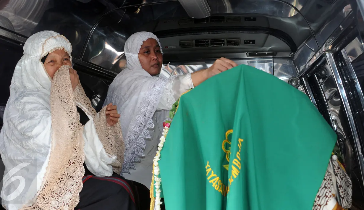 Istri Ketua KPU Husni Kamil Manik merapikan letak untaian bunga di atas keranda jenazah suaminya usai disalatkan di Kompleks KPU, Jakarta, Jumat (8/7). Husni Kamil Manik wafat diusia 40 tahun pada Kamis malam (7/7). (Liputan6.com/Helmi Fithriansyah)