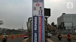 Kendaraan melintasi alat peraga kampanye (APK) yang terpasang di kawasan Depok, Jawa Barat dan Ciputat, Tangerang Selatan, Minggu (18/10/2020). KPU Kota Tangsel dan Depok membagikan sejumlah alat peraga kampanye kepada pasangan calon Pilkada 2020 serentak. (Liputan6.com/Johan Tallo)