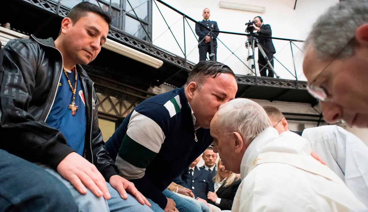 Paus Fransiskus mendapat ciuman seorang narapidana usai mencuci dan mencium kakinya selama berkunjung ke pusat penahanan di Roma, Italia, Kamis (29/3). Kunjungannya ini untuk merayakan "Missa in Coena Domini". (Vatican Media via AP)