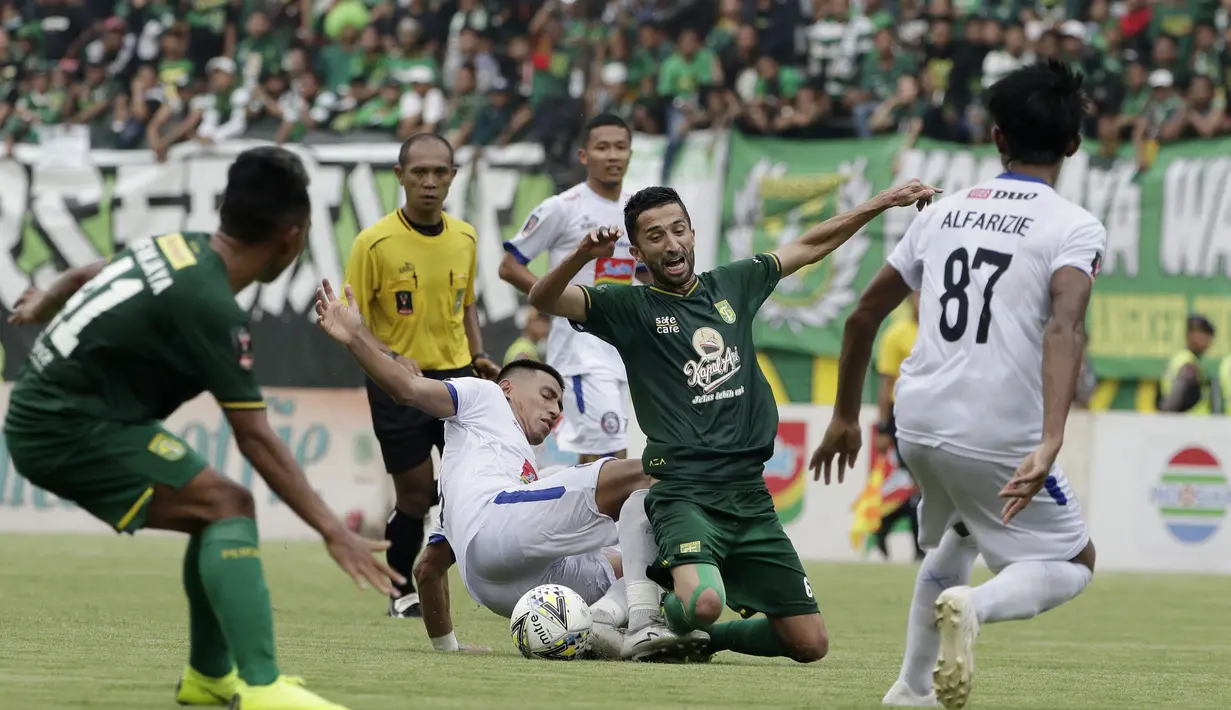 Penyerang Persebaya Surabaya, Manuchekhr Dzhalilov, terjatuh saat berebut dengan pemain Arema FC, Hanif Sjahbandi, pada laga final Piala Presiden 2019 di Stadion Gelora Bung Tomo, Selasa (9/4). Kedua tim bermain imbang 2-2. (Bola.com/Yoppy Renato)