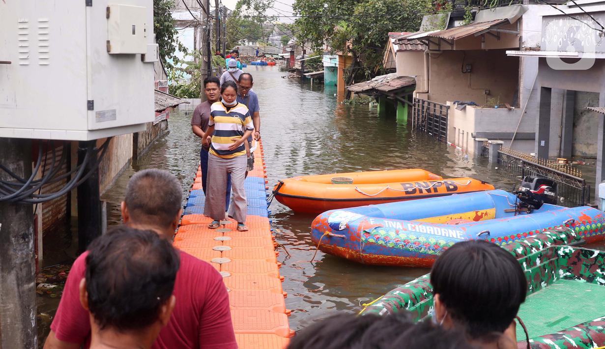 Warga berjalan melintasi jembatan apung saat banjir melanda Perumahan Periuk Damai, Tangerang, Banten, Selasa (23/2/2021). Adanya jembatan apung mempermudah warga saat melintasi banjir setinggi 2,5 meter di tempat tersebut. (Liputan6.com/Angga Yuniar)