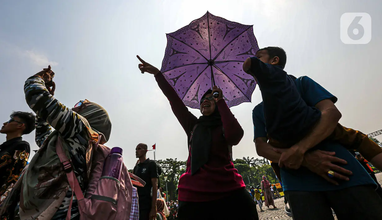 Sekilas, warga terlihat seperti berpiknik. Ada yang bawa bekal dan minuman. Namun, ada juga yang berdiri sambil siap dengan ponsel di tangan. (Liputan6.com/Faizal Fanani)