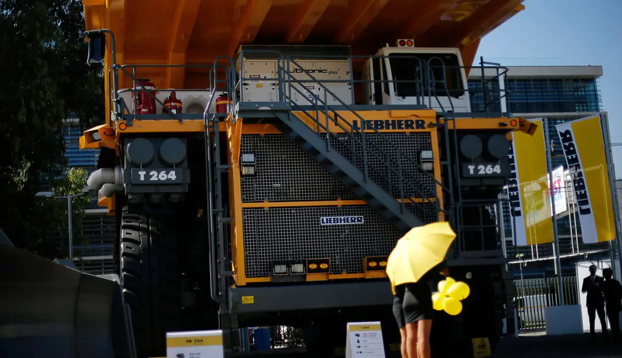 Salah satu SPG berdiri di depan sebuah truk pertambangan yang dipamerkan dalam ajang "Expomin 2014", sebuah pameran dua tahunan pertambangan di Santiago, Chili, (21/4/2014). (REUTERS/Ivan Alvarado)