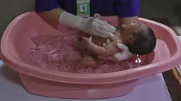 Perawat memandikan seorang bayi saat kegiatan pelatihan di RSIA Tambak, Jakarta, Kamis (18/02/2021). Melatih para ibu baru untuk memandikan bayi pertama tersebut dilakukan dengan menerapkan protokol kesehatan ketat. (Liputan6.com/Herman Zakharia)