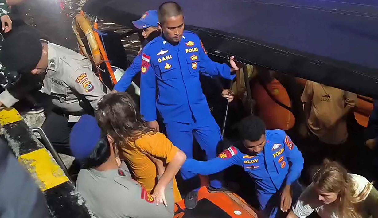 Kapal wisata berbendera Indonesia itu diketahui mengangkut 11 orang, terdiri dari awak kapal, pemandu wisata, dan penumpang, termasuk wisatawan mancanegara asal Spanyol. Tampak foto yang dirilis pada 27 Desember 2025 oleh Badan Nasional Pencarian dan Penyelamatan Indonesia (BASARNAS) Labuan Bajo ini menunjukkan anggota tim pencarian dan penyelamatan mengevakuasi wisatawan asing di perairan Pulau Padar, Labuan Bajo, Nusa Tenggara Timur, setelah sebuah kapal wisata mengalami kerusakan mesin dan tenggelam. (Handout/BASARNAS/AFP)