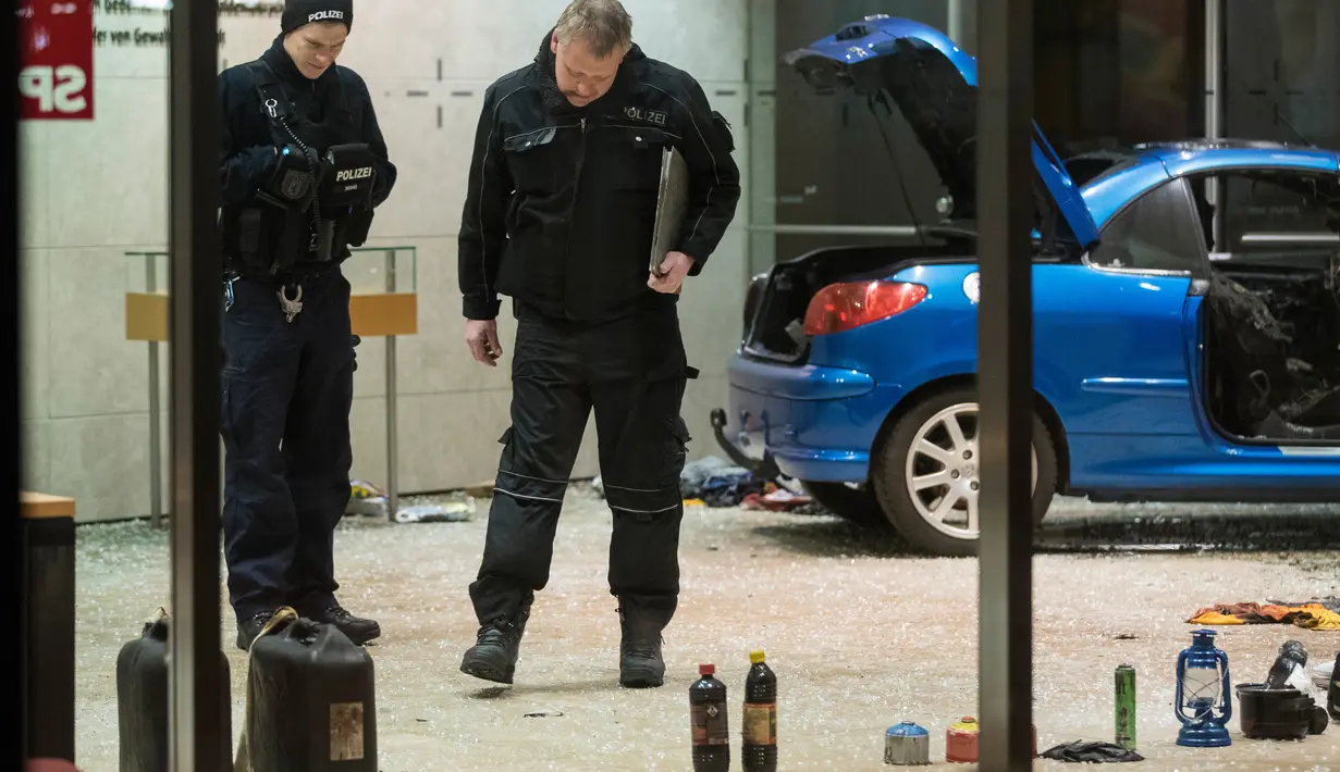 Polisi memeriksa tabung bensin dan cairan dari dalam mobil di lobi kantor Partai Sosial Demokratik Jerman (SPD) setelah sebuah mobil menabrakan gedung di Berlin (25/12). Menurut keterangan polisi, pelaku ingin bunuh diri. (AFP PHOTO / Ganjil Andersen)