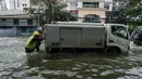 Orang-orang mendorong kendaraan yang mogok di jalan yang banjir di pinggiran Yangon, Myanmar  (17/8/2022). Hujan lebat sejak larut malam 16 Agustus menyebabkan kemacetan lalu lintas dan kesulitan bagi para komuter di kota Yangon dengan beberapa jalan masih terendam banjir.  (AFP/Stringer)