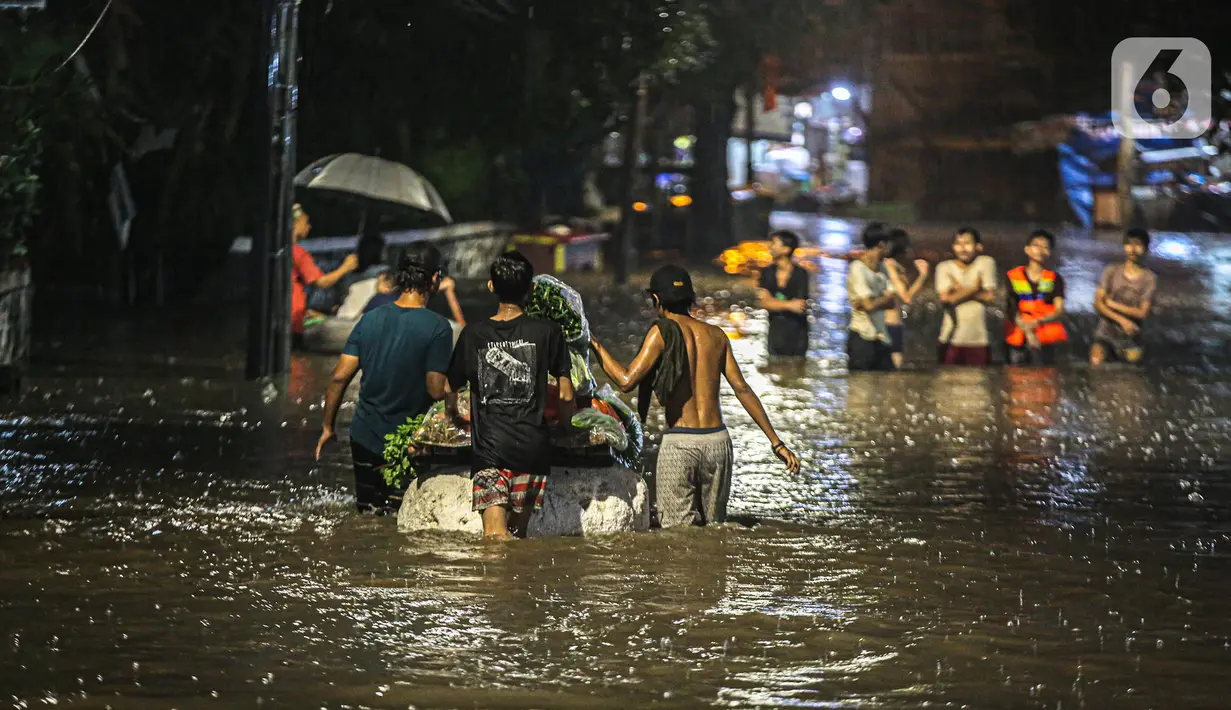 Sejumlah warga melintasi genangan banjir di kawasan Kemang, Jakarta, Selasa (4/10/2022). Jalan Kemang Utara IX tak bisa dilalui oleh kendaraan. Banjir menggenangi kawasan Pasar Kambing dan sejumlah rumah penduduk. (Liputan6.com/Faizal Fanani)