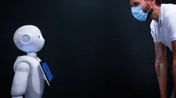 Seorang pria yang memakai masker melihat ke arah robot Pepper di SoftBank Robotics di Paris, Prancis (10/9/2020). Dengan fitur baru, robot Pepper mampu mendeteksi apakah orang-orang memakai masker, dan jika ada yang tidak memakai masker, dia akan memerintahkan mereka untuk memakainya. (Xinhua/Aureli