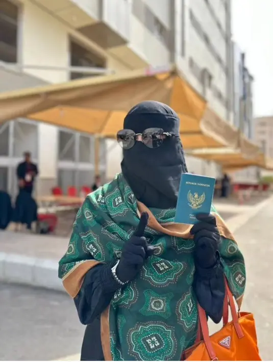 Berada di Arab Saudi, Umi Pipik mencoblos dengan gamis dan cadar hitam dipadukan pashmina hijau sambil membawa tas Prada orange. [@_ummi_pipik_]