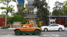 Truong Van Dao melewati sebuah rumah dengan tank kayu di daerah perumahan di provinsi Bac Ninh pada 28 Maret 2022. Seorang ayah di Vietnam telah menghabiskan ratusan jam dan menginvestasikan uangnya untuk mengubah mobil van tua menjadi tank kayu untuk putranya. (Nhac NGUYEN /AFP)