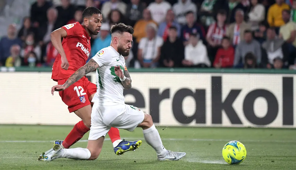 <p>Bek Atletico Madrid Renan Lodi (kiri) berebut bola dengan gelandang Elche CF Josan pada jordana ke-36 La Liga Spanyol 2021/2022 di Estadio Martinez Valero, Kamis (12/5/2022) dini hari WIB. Atletico Madrid sukses menaklukkan tuan rumah Elche dengan skor meyakinkan 2-0. (JOSE JORDAN / AFP)</p>