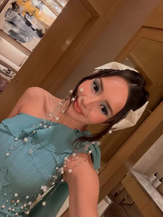 Gaun yang dikenakannya hadir dalam nuansa hijau kebiruan, memberikan kesan segar dan elegan sekaligus. Potongan asimetris dengan aksen lipit-lipit halus pada bagian rok menciptakan efek ombak yang mengalun, seolah menggambarkan keindahan bawah laut.  [@bebytsabina].